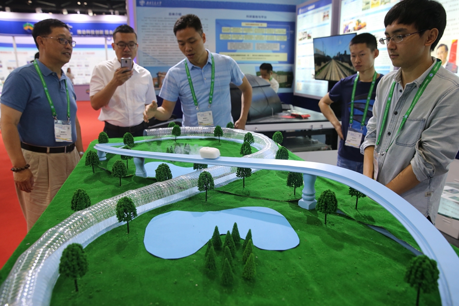 Visitors observe the model of a superconducting tube maglev at the 2018 World Transport Convention in Beijing on Tuesday. [Photo: China Daily]
