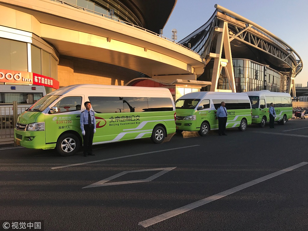 Drivers stand beside minibuses to be used for a new online bus-pooling service at the Beijing South Railway Station, September 22, 2018. [Photo: VCG]